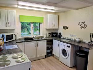 a kitchen with white cabinets and a washer and dryer at Studio cottage in Tummel Bridge