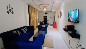a living room with blue couches and a flat screen tv at Five BHK Abode in Golf City Lucknow in Nalmatha