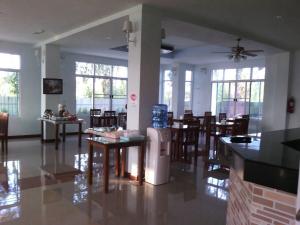 a dining room with tables and chairs and windows at Baan Duangkamol in Phitsanulok