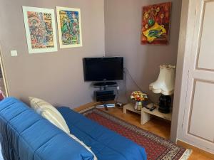 a living room with a blue couch and a flat screen tv at T2 cœur de ville La Londe-Les-Maures in La Londe-les-Maures
