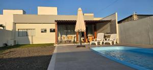 a house with a swimming pool and an umbrella at Casa Temporada Sereia do Mar in São Mateus