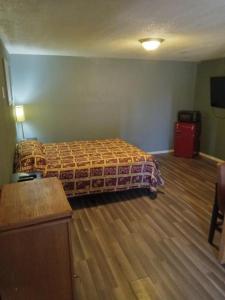 ein Schlafzimmer mit einem Bett und einem Holzboden in der Unterkunft Ranch Motel in Roswell