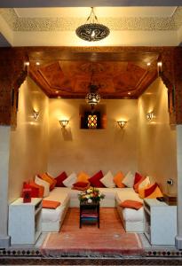 a living room with a white couch with colorful pillows at Riad Charik in Marrakesh