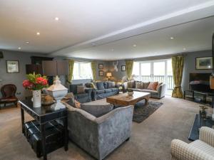 a living room with couches and a table at Nant-yr-Rhedyn in Benllech
