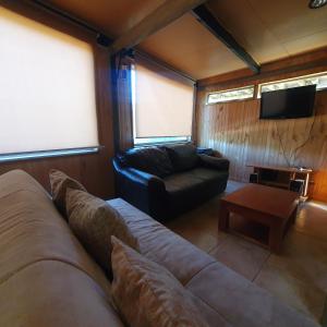 a living room with a couch and a tv at Remodelada Cabaña Antoleo a metros de Lago Vichuquén in Vichuquén
