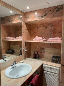 a bathroom with a sink and shelves with towels at Salusahome parking gratuito in Córdoba