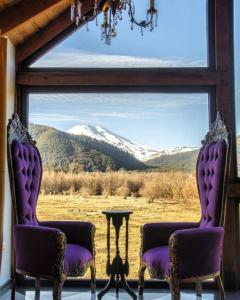 two chairs in front of a window with a mountain view at Spectra Lodge Boutique Hotel in Malalcahuello