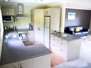 a kitchen with white cabinets and a black counter top at Franz Josef Treetops in Franz Josef