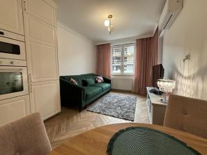 a living room with a green couch and a television at Apartamenty w centrum Białegostoku z parkingiem w garażu podziemnym in Białystok