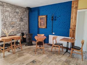a room with a blue wall and wooden tables and chairs at Vila Nikol in Voskopojë