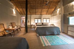 a bedroom with two beds and a table and chairs at Tiger Tops Tharu Lodge in Chitwan