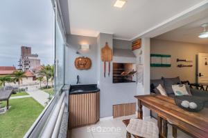 a room with a balcony with a couch and a table at Apto moderno e confortável perto da praia JSR112 in Florianópolis