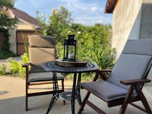 two chairs and a table with a candle on a patio at Éva Pihenőház Tiszaföldvár in Tiszaföldvár
