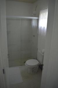 a white bathroom with a toilet and a shower at Pousada JMedina Maresias in Maresias