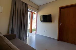 a living room with a couch and a flat screen tv at Villa di kona in Serra Negra