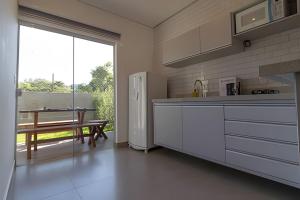 a kitchen with a white refrigerator and a table with a bench at Villa di kona in Serra Negra
