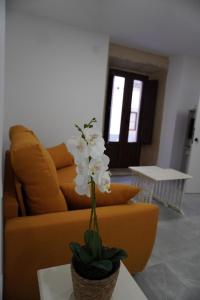 un divano giallo con un vaso di fiori su un tavolo di APARTAMENTO Sanin 2 a Lumbrales