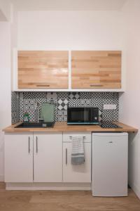 a kitchen with white cabinets and a microwave at Appartement T1 bis L'enfilade in Albi +10 photos