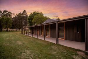 a large building with a grass field in front of it at The Stables Nug Nug Ranch in Buffalo River