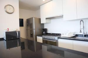 坎昆Luxury Apt with Balcony, Marina Puerto Cancún的厨房配有白色家电和墙上的时钟
