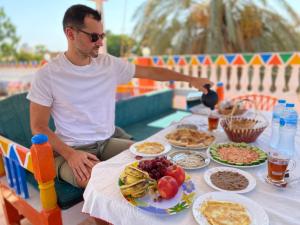 a man sitting at a table with food on it at La Veranda 陽台 in Aswan