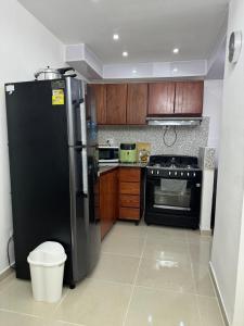 Una cocina con refrigerador negro y gabinetes de madera. en Casa las América, en La Cana