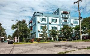 拉塞瓦狂欢节酒店的一座蓝白色的建筑,种植了棕榈树,街道上
