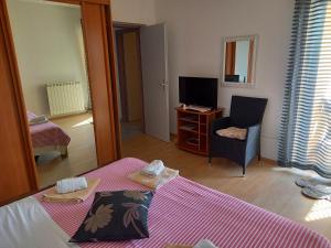 a room with a bed and a chair and a television at LEVANDA in Supetarska Draga