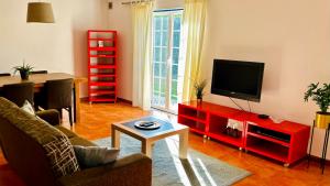 a living room with a tv and a red entertainment center at Charmoso Apartamento T2 em Foros de Salvaterra in Monte de Lucas