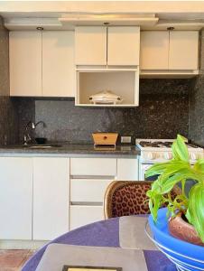 ポルラマルにあるTorremolinos Apartamento estilo Rústico con excelente ubicaciónの白いキャビネットと植物が置かれたテーブルのあるキッチン