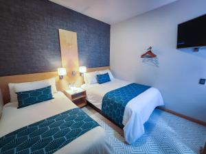 a hotel room with two beds and a flat screen tv at HOTEL AZUL AGAVE in Arandas
