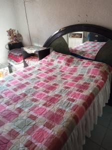 a bed with a pink and white quilt on it at hacienda los tulipanes in Monterrey