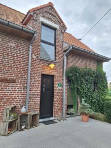 a brick house with a black door and a window at le Repaire des Loups in La Basse Ville