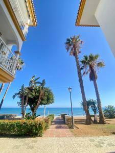 a walkway next to the beach with palm trees at First Line Torrox Costa in Torrox Costa +35 photos