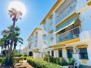 a building with palm trees in front of it at First Line Torrox Costa in Torrox Costa