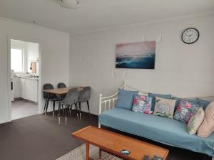 a living room with a blue couch and a table at Nesting In Hamilton East in Hamilton