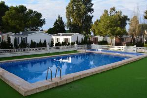 a swimming pool in a yard with a white fence at Camping Valencia el Saler in El Saler