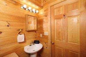 a bathroom with a white sink and a wooden wall at Thunder Bear Hideaway Roar Into Relaxation in Pigeon Forge +33 photos