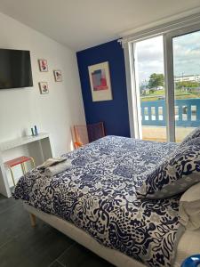 a bedroom with a bed and a large window at Le logis de l estuaire in Meschers-sur-Gironde