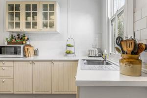 a white kitchen with a sink and a microwave at Meroo Meadow Magic Charming Cottage Retreat in Meroo