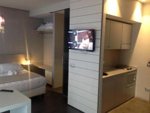 ベッラーリア・イジェア・マリーナにあるベル スイート ホテルのベッド1台、壁掛けテレビが備わる小さな客室です。