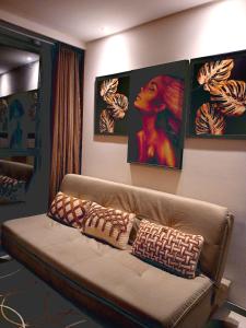 a couch in a living room with paintings on the wall at Luxury Paiva Flat in Recife