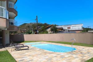 a swimming pool with two chairs next to a building at Mareazul Ubatuba in Ubatuba