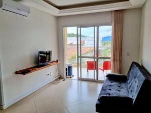 a living room with a couch and a television at Mareazul Ubatuba in Ubatuba