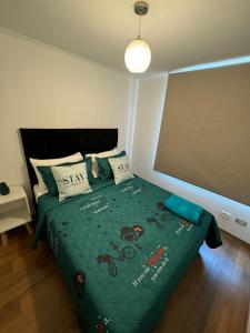 a bedroom with a bed with a green comforter at Apartamentos Orquídea Suite in Santiago