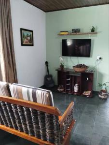 a living room with a couch and a flat screen tv at Canto Verde casa de veraneio, férias e piscina in Cananéia