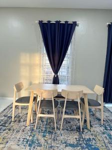 a dining room table with chairs and a blue curtain at QU Homestay Kuala Terengganu in Kuala Terengganu +1 photo