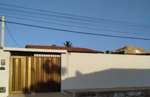 ein weißes Gebäude mit einer Holztür darauf in der Unterkunft Casa de Temporadas Alto Bonito in Luis Correia