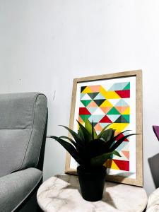 a potted plant sitting on a table next to a painting at 28 OFF Affordable Beautiful Queen Bedroom Near City Swan River Fremantle University in Perth