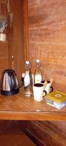 two glass bottles on a wooden shelf with a tea kettle at Cool Banyan Cabana in Trincomalee